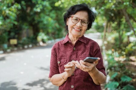Smiling Asian Senior Woman Smiling with Smartphone in hand